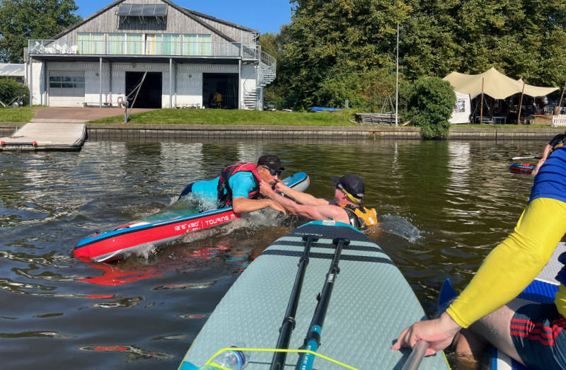 SUP Ausbildung: Zwei Teilnehmende führen im Wasser eine Sicherheitsübung aus.